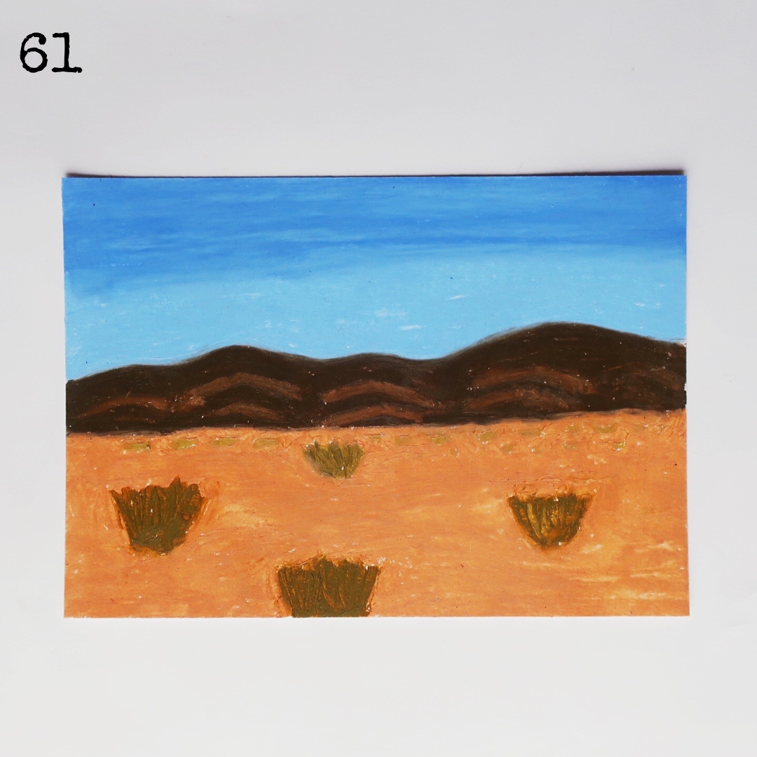 An oil pastel painting of a desert scene with the mountain under a blue sky