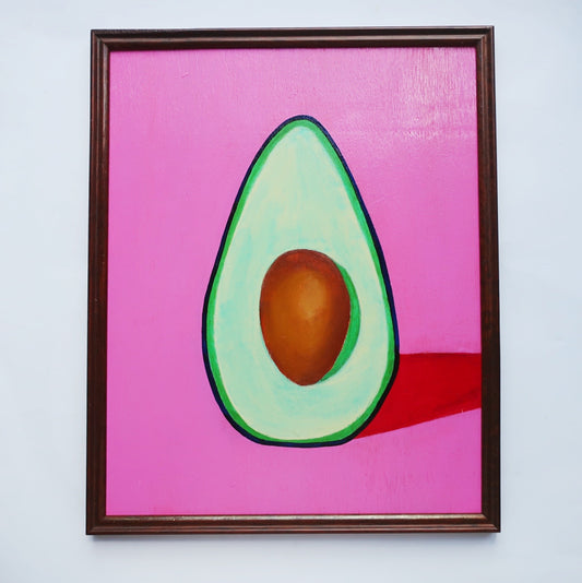 An oil painting of a green avocado on a pink background in a thrifted frame