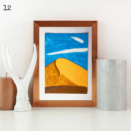 A brown framed oil pastel painting of a desert dune under the blue sky