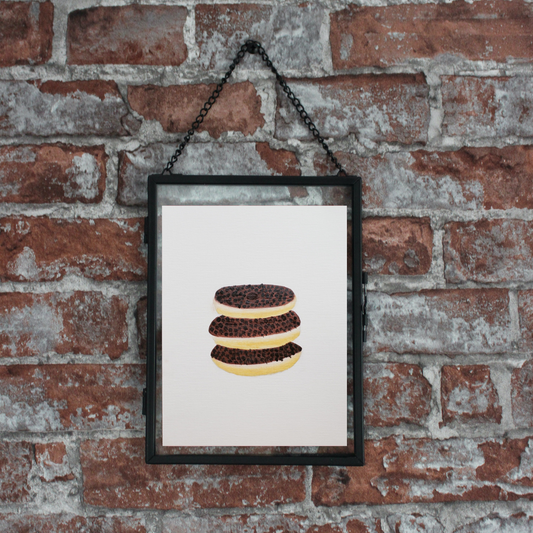 A framed oil painting of three donuts with chocolate chips