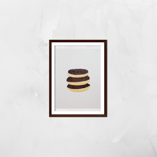 A framed oil painting of three donuts with chocolate chips on a white wall