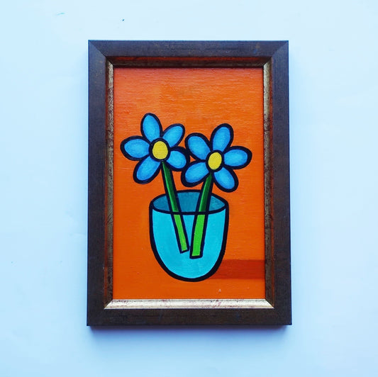 An oil painting of blue flowers on an orange background in a thrifted frame