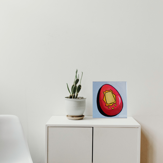 An oil painting of a red tamagotchi game against a blue background on a white cabinet