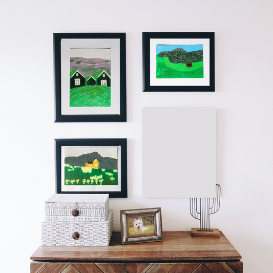 Three black framed oil pastel paintings of cute houses at the mountain side in a boho decor