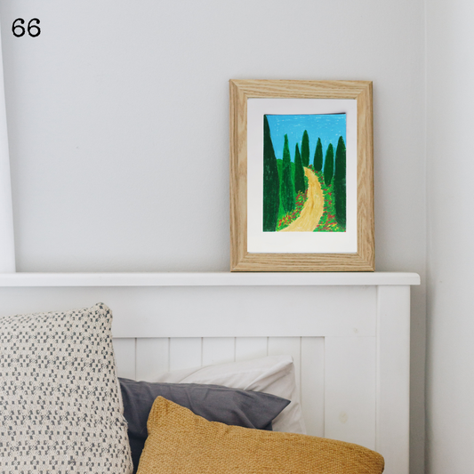 A wooden framed oil pastel painting of an earth track with trees