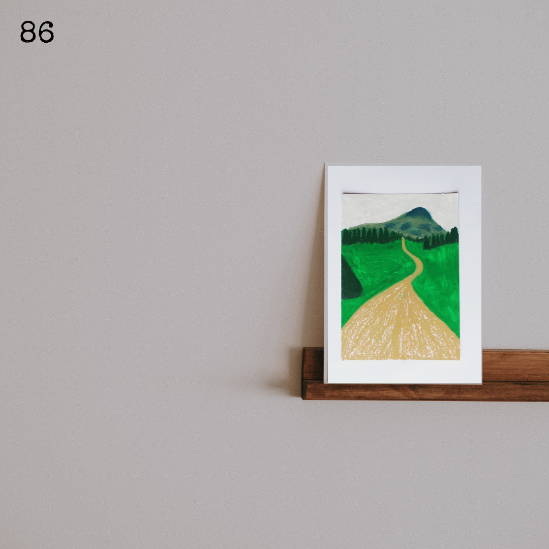 An oil pastel painting of an earth track leading to a mountain on a wooden shelf