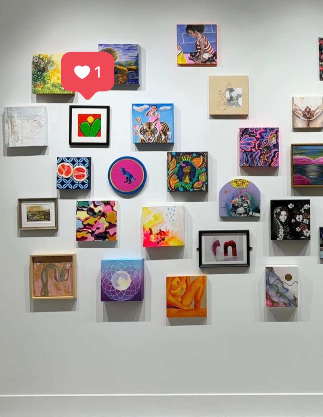 A black framed oil painting of two green leaves under a rising sun on a red background in a group exhibition