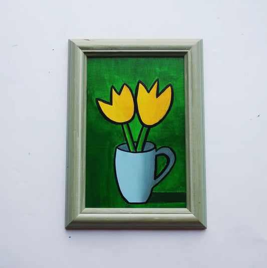 An oil painting of two yellow tulips in a blue mug on a green background in a thrifted frame