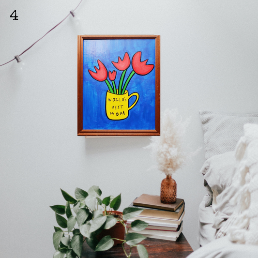 An oil painting of four red tulips in a yellow mug with the words world's best mom on a blue background in a thrifted frame in a boho decor