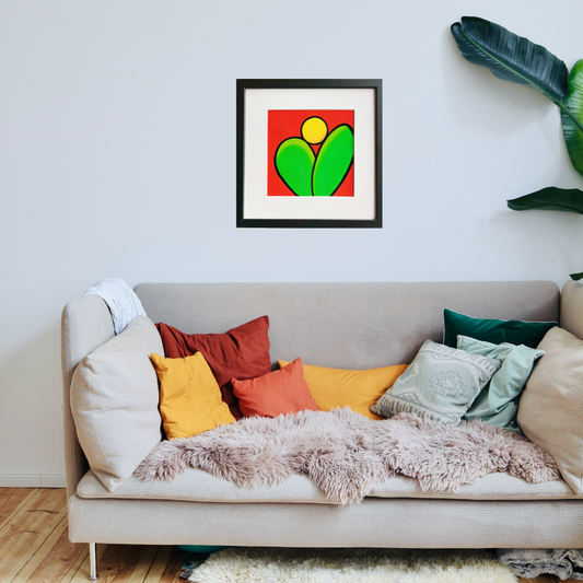 A black framed oil painting of two green leaves under a rising sun on a red background in a boho living room