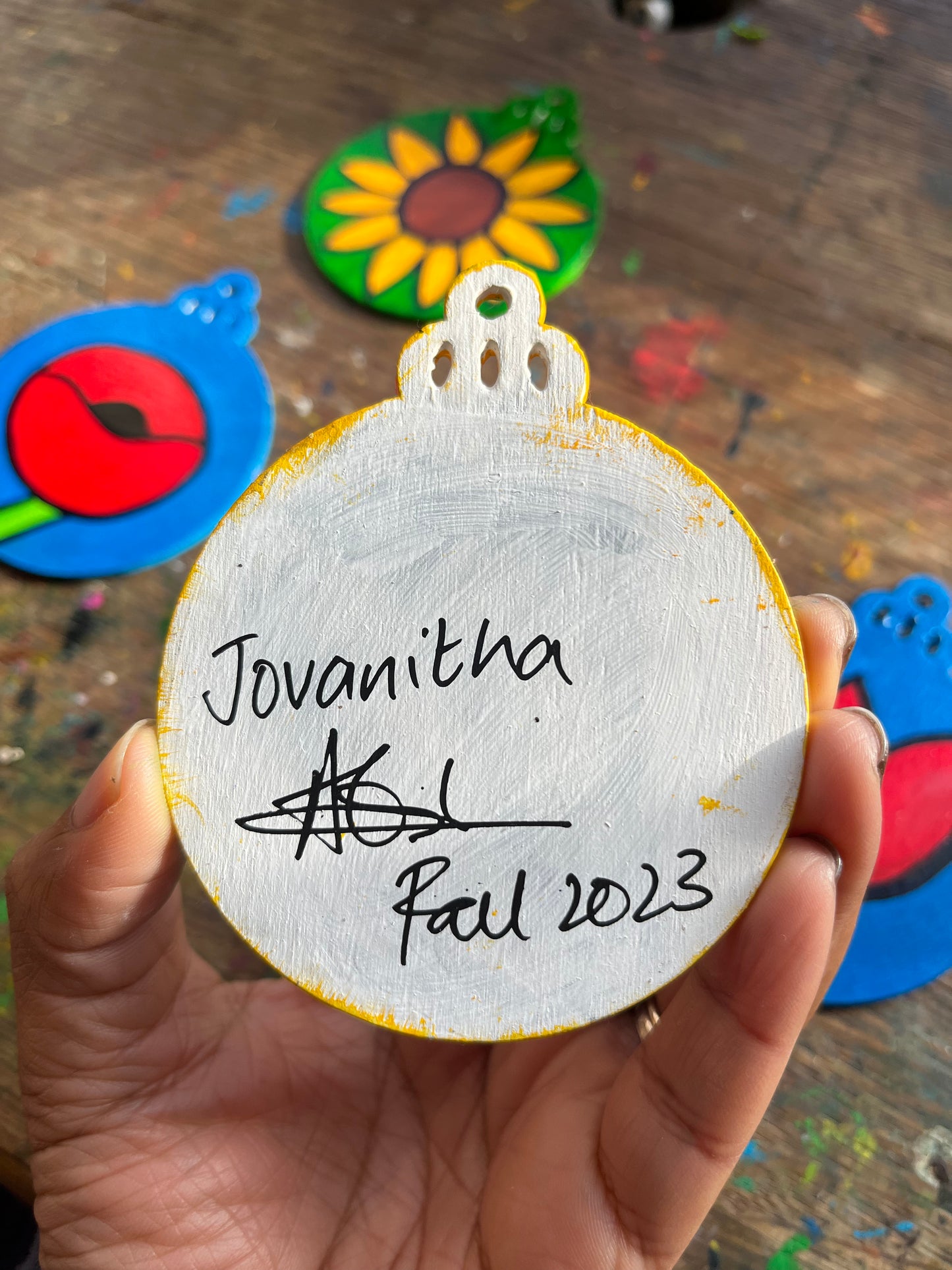 The back of a Christmas ornament with the artist's signature