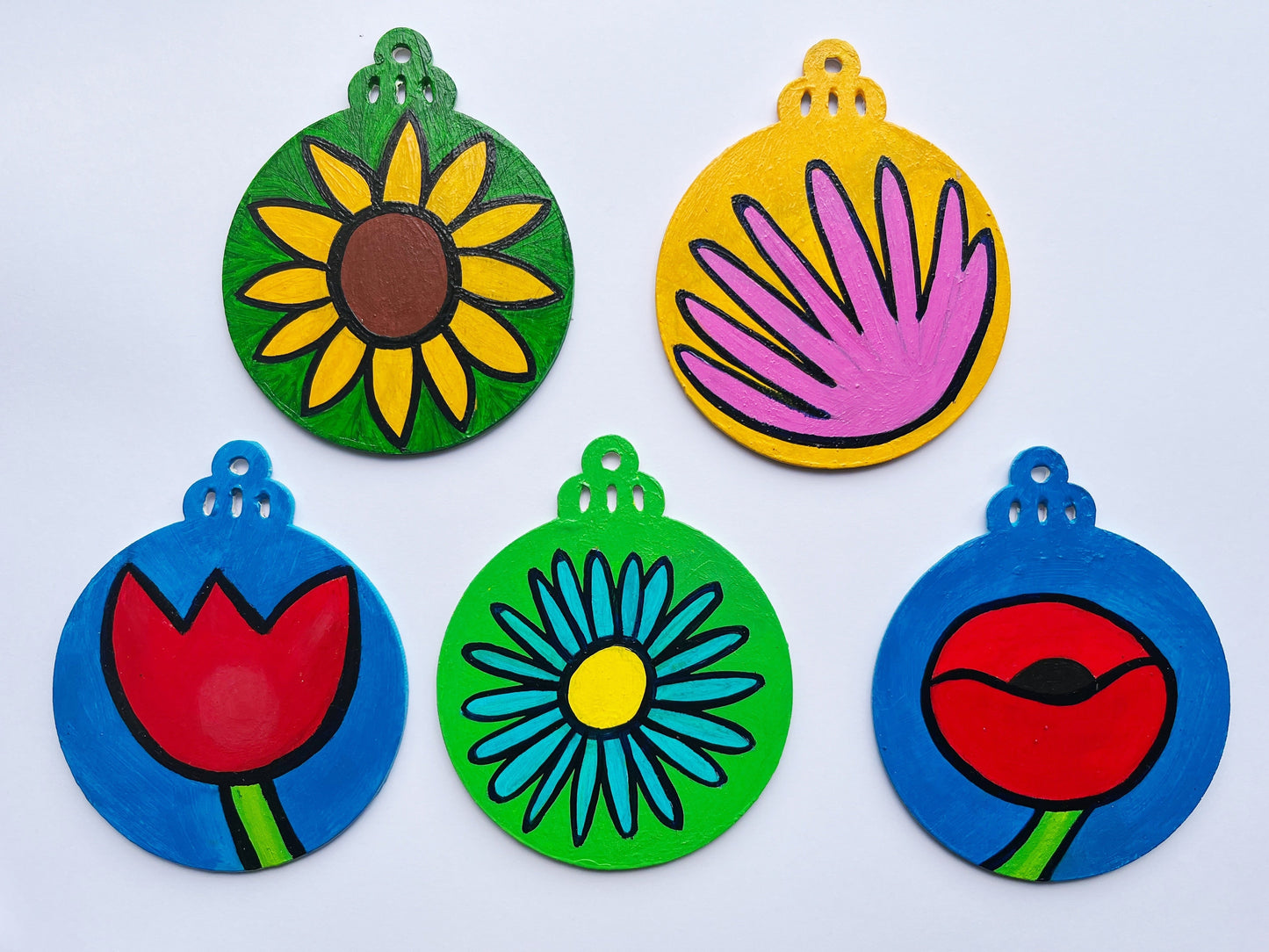 Five colorful wooden Christmas ornaments representing flowers 