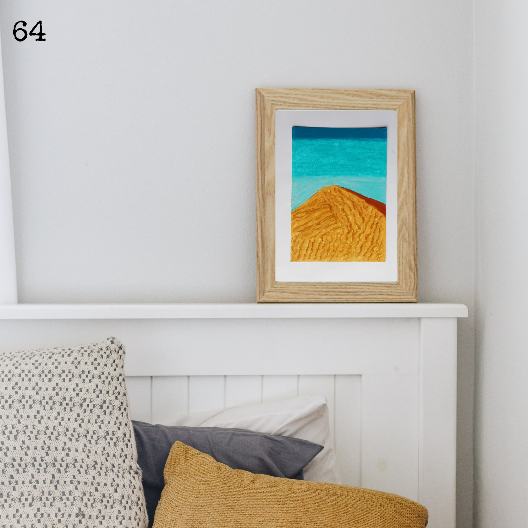 A framed oil pastel painting of a desert dune under the blue sky