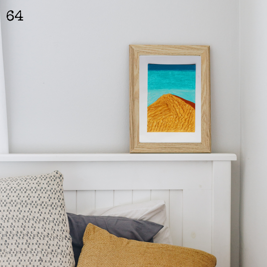 A framed oil pastel painting of a desert dune under the blue sky