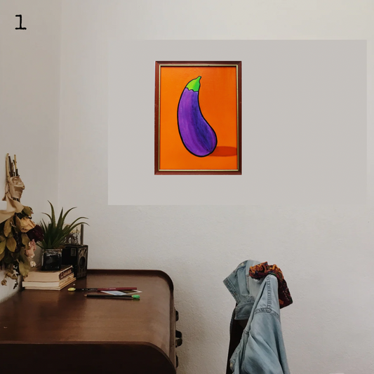 An oil painting of a purple eggplant on an orange background in a thrifted frame in a boho office