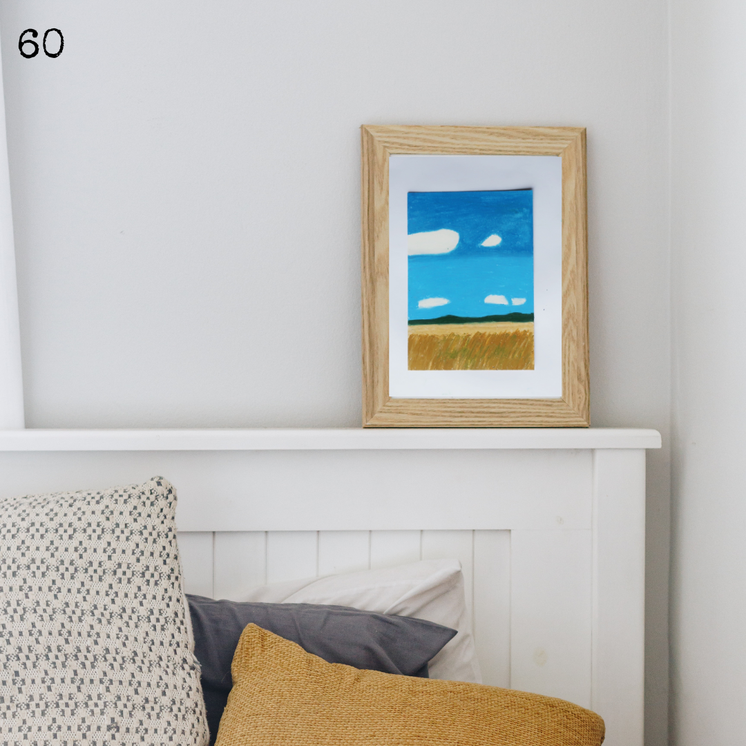 A wooden framed oil pastel painting of a field of wheat during the summer