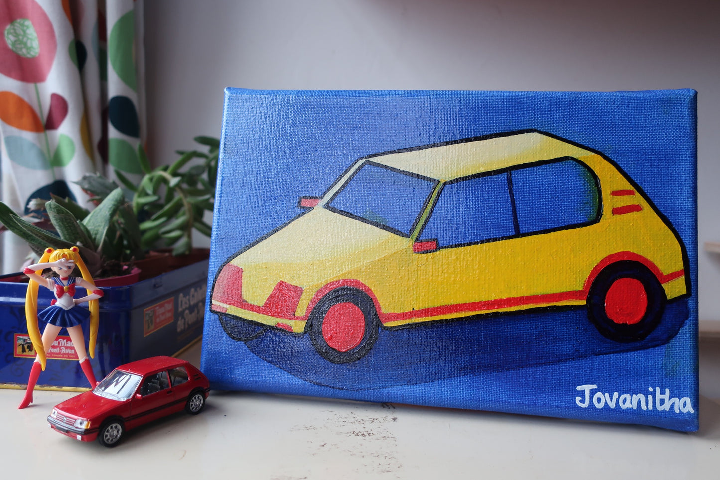 An oil painting of a yellow Peugeot 205 car against a blue background on a white shelf