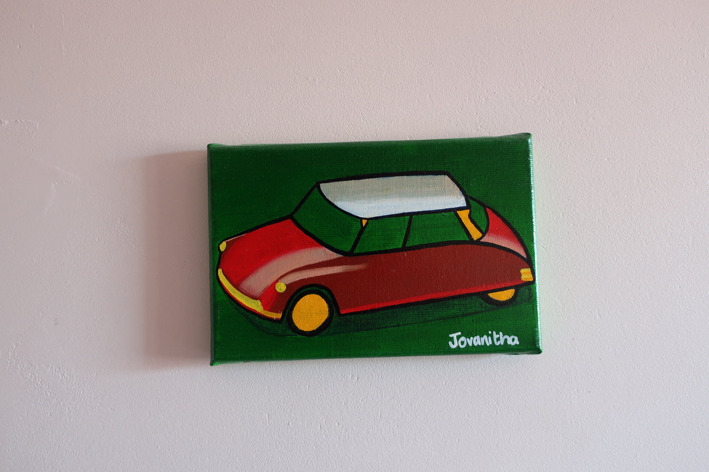 An oil painting of a red Citroen DS car against a green background on a white wall