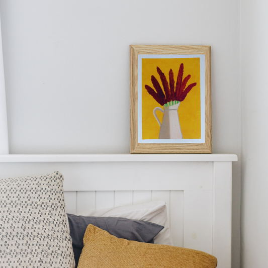 A wooden framed oil painting of lilac flowers in a white vase against a yellow background on a white chimney mantle