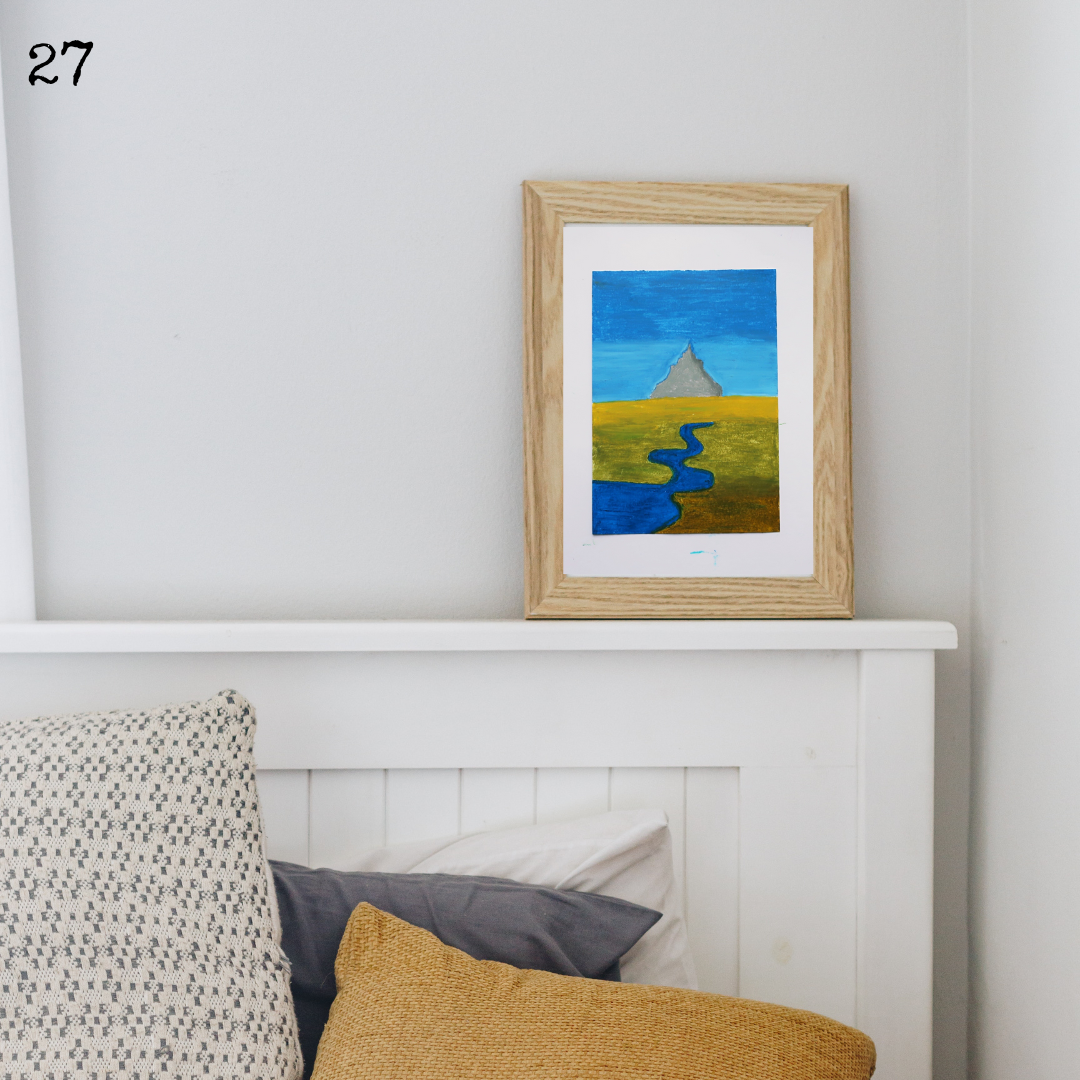 A wooden framed oil pastel painting of the mont St Michel on a white mantelpiece