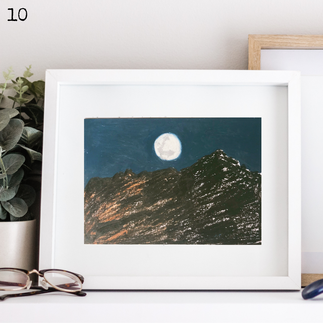 A white framed oil pastel painting of a mountain at night with the moon