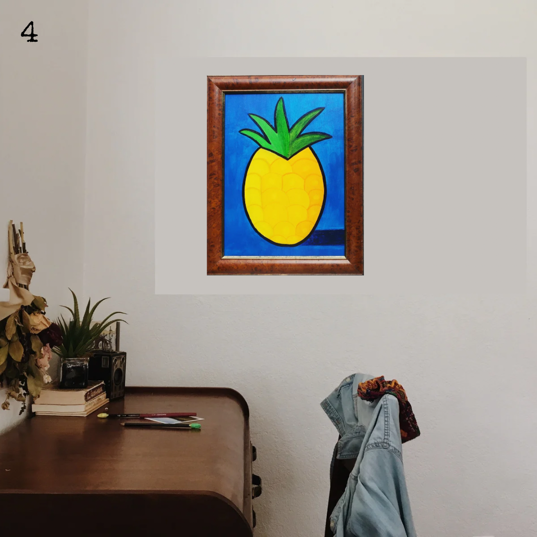 An oil painting of a yellow pineapple on a blue background in a thrifted frame in a boho decor