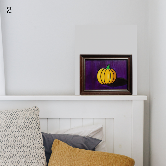 An oil painting of a yellow pumpkin on a purple background in a thrifted frame in a boho decor