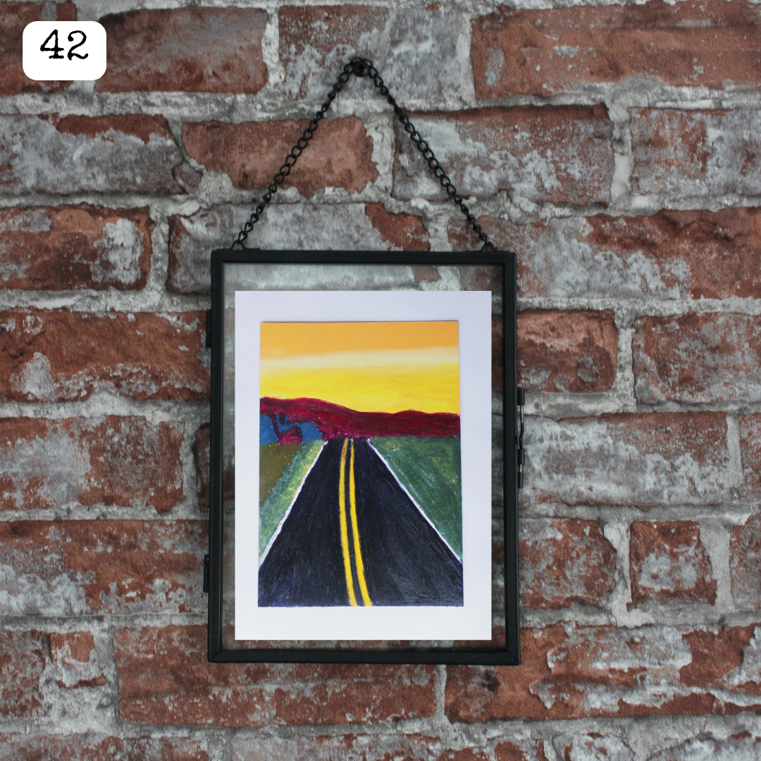A black framed oil pastel painting of a black road and sunrise
