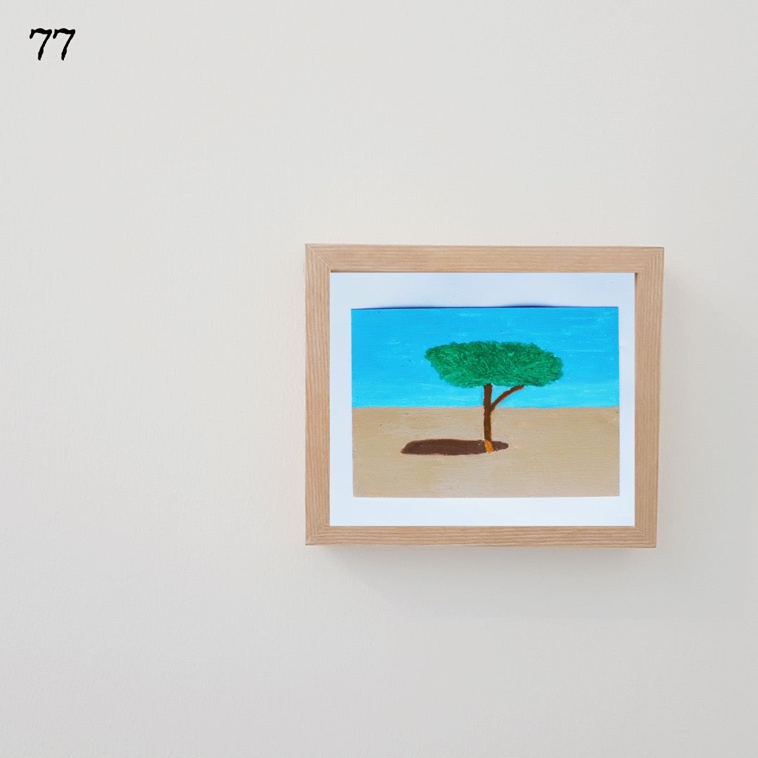 A wooden framed oil pastel painting of a tree in the desert